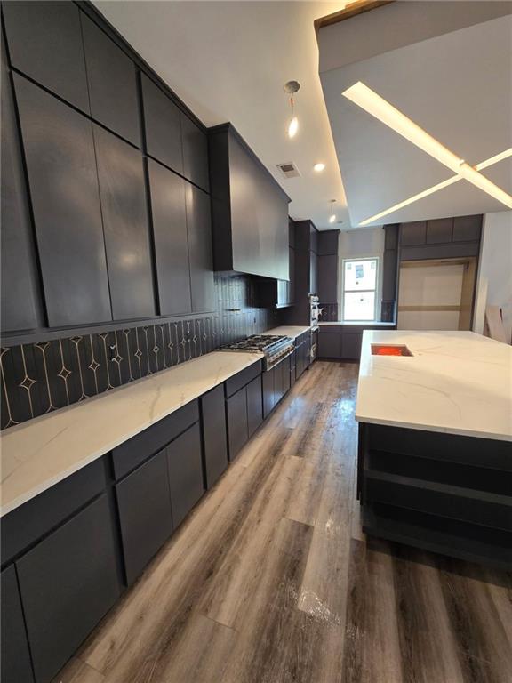300 Mountain Ridge Dr, Dahlonega, GA 30533 - kitchen with light stone countertops, visible vents, stainless steel gas cooktop, wood finished floors, and backsplash