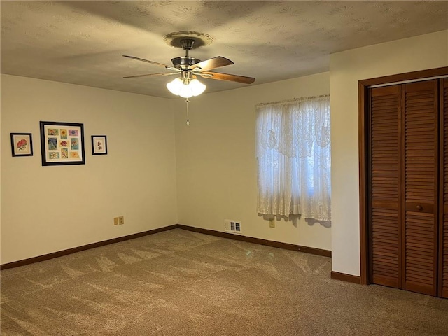 unfurnished bedroom with carpet flooring, a closet, ceiling fan, and a textured ceiling