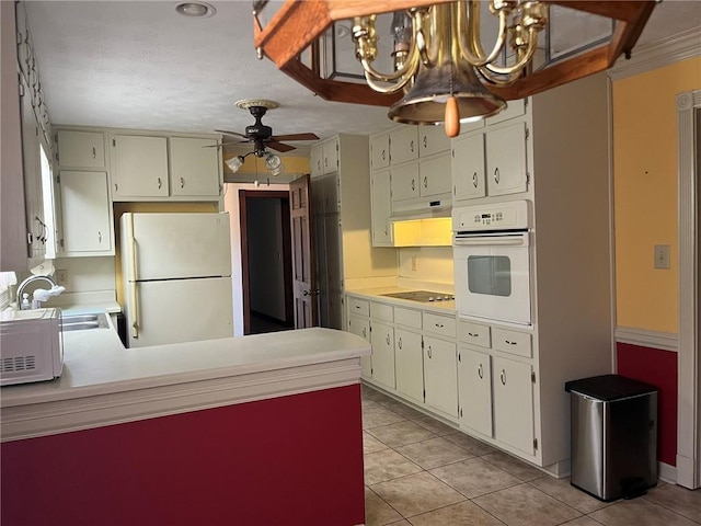 kitchen with white appliances, light tile patterned floors, ceiling fan with notable chandelier, white cabinets, and sink