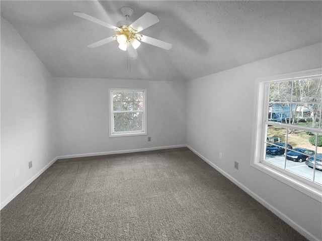 carpeted empty room featuring ceiling fan, lofted ceiling, and a wealth of natural light