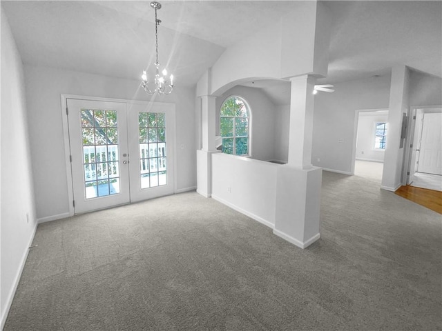 empty room featuring carpet flooring, ornate columns, a chandelier, and vaulted ceiling