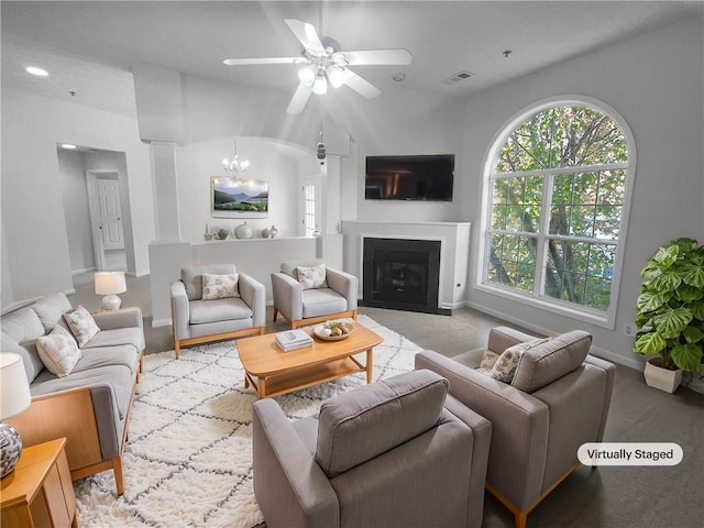 living room with ceiling fan with notable chandelier and vaulted ceiling