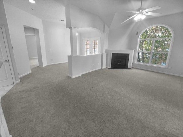 unfurnished living room featuring carpet flooring, decorative columns, vaulted ceiling, and ceiling fan