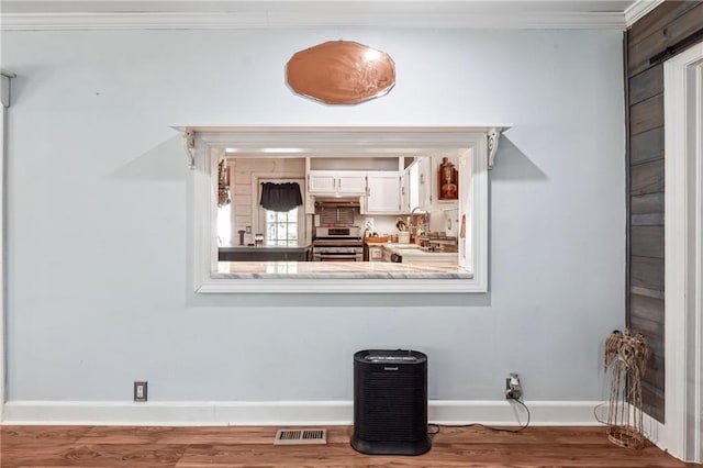 details featuring stainless steel stove, hardwood / wood-style flooring, and crown molding