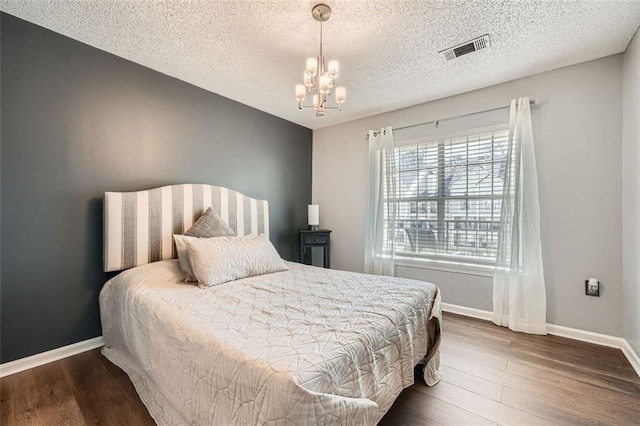 bedroom with dark wood-style flooring, visible vents, a notable chandelier, and baseboards