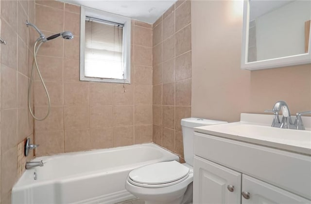 full bathroom featuring tiled shower / bath, vanity, and toilet