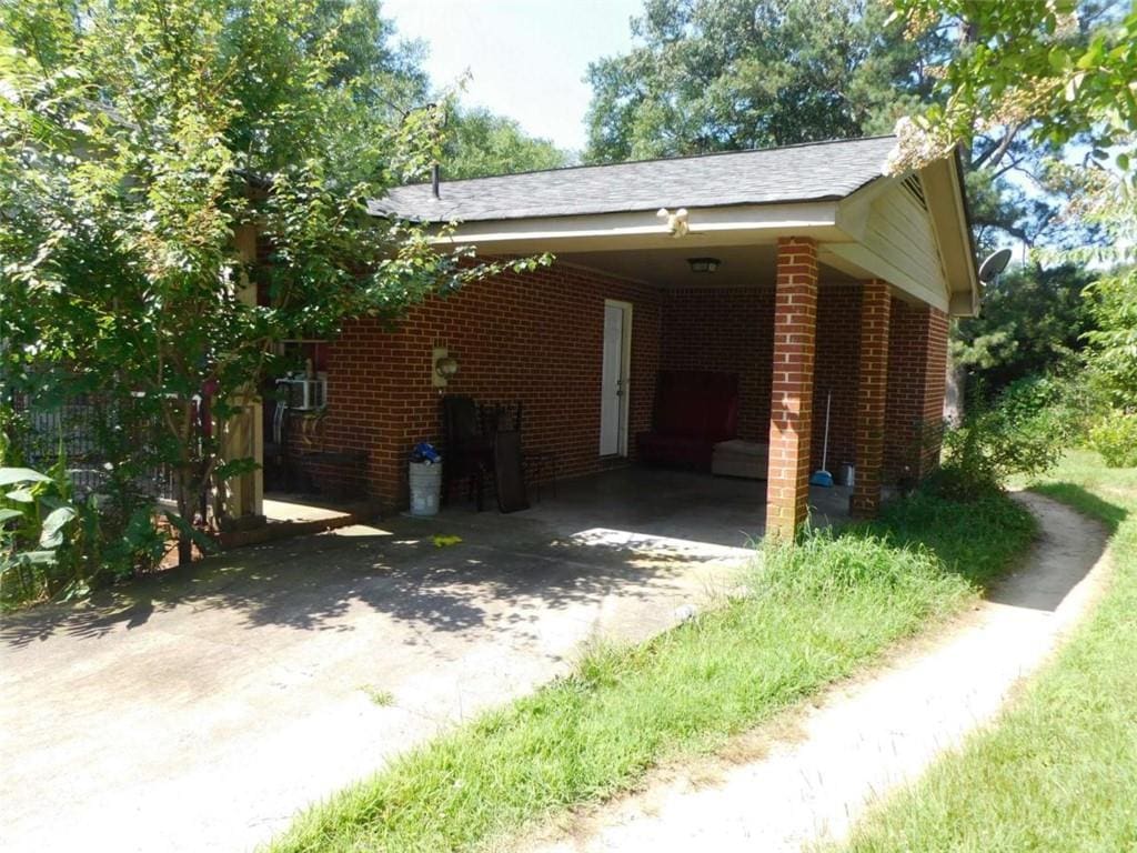 165 Shields St, Winder, GA 30680 - view of side of property with concrete driveway, brick siding, an attached carport, and roof with shingles