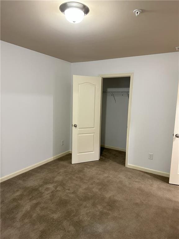 unfurnished bedroom featuring a closet and dark colored carpet