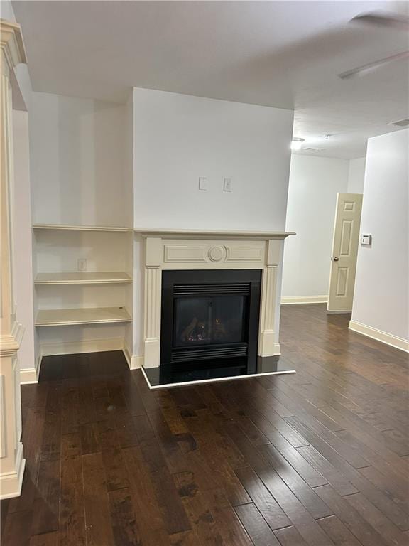 unfurnished living room featuring ceiling fan and dark hardwood / wood-style floors