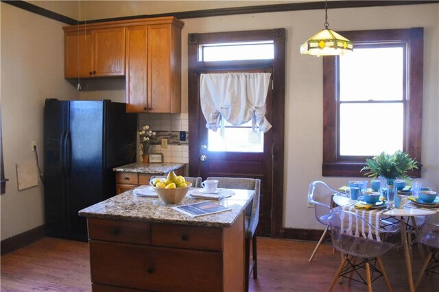 kitchen with brown cabinetry, plenty of natural light, black refrigerator with ice dispenser, and decorative backsplash