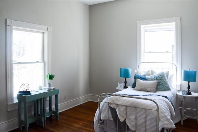 bedroom featuring baseboards, wood finished floors, and multiple windows