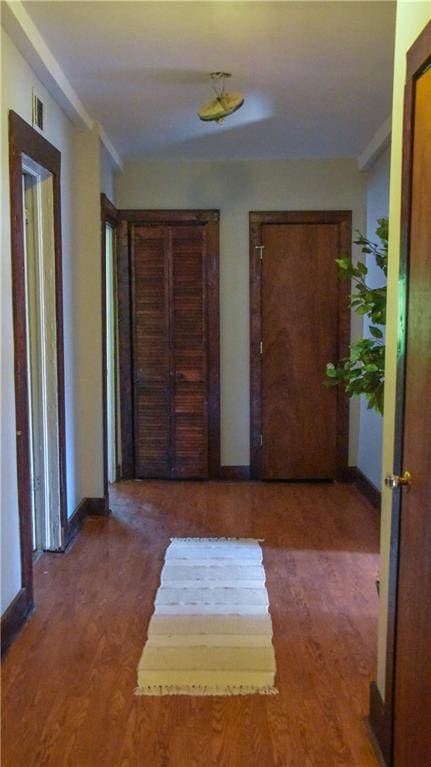 hall featuring baseboards, visible vents, and wood finished floors