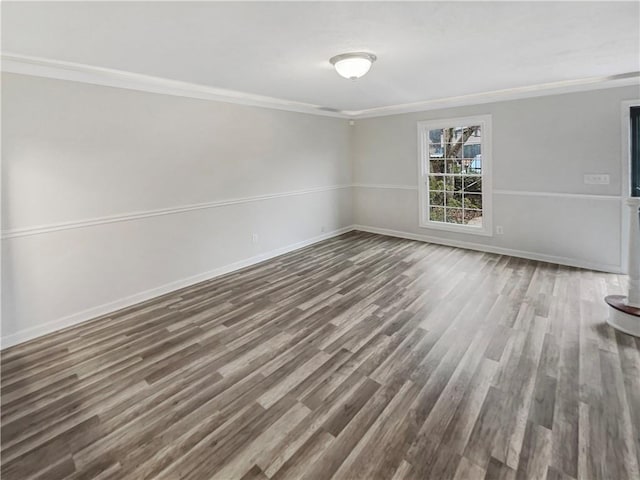 empty room with baseboards, dark wood-type flooring, and ornamental molding