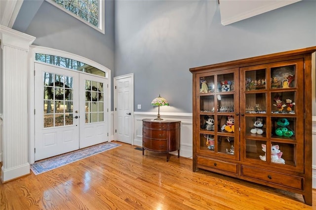 entryway featuring french doors, light wood-type flooring, and a high ceiling