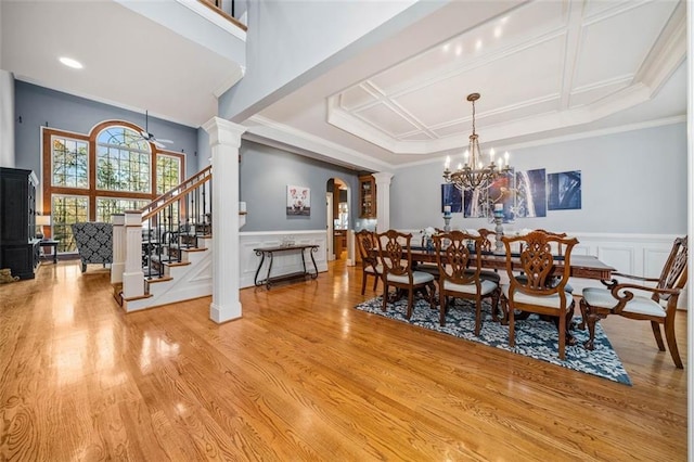 dining space with ceiling fan with notable chandelier, light hardwood / wood-style floors, crown molding, and coffered ceiling