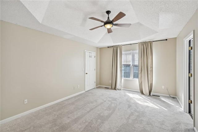 carpeted spare room featuring a tray ceiling, baseboards, a textured ceiling, and ceiling fan