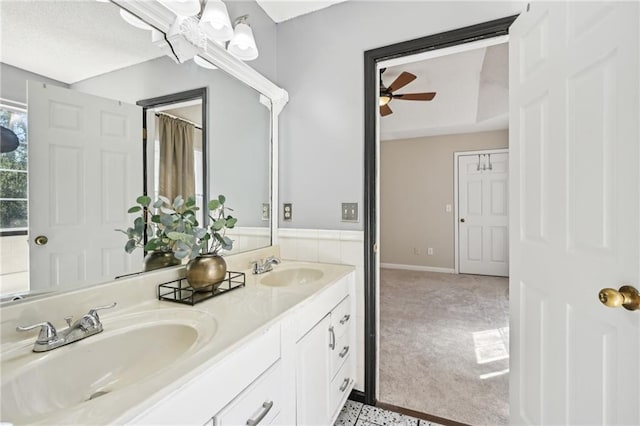 full bathroom featuring double vanity, baseboards, ceiling fan, and a sink