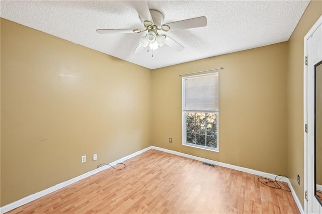 unfurnished room featuring baseboards, visible vents, light wood-style flooring, ceiling fan, and a textured ceiling