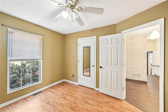 unfurnished bedroom with light wood-type flooring, baseboards, visible vents, and a textured ceiling