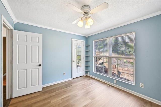 empty room featuring a textured ceiling, wood finished floors, and ornamental molding