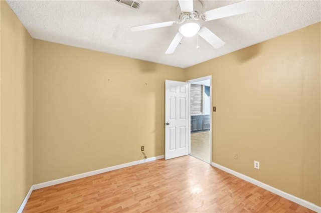 unfurnished room with a ceiling fan, visible vents, light wood-style floors, and baseboards