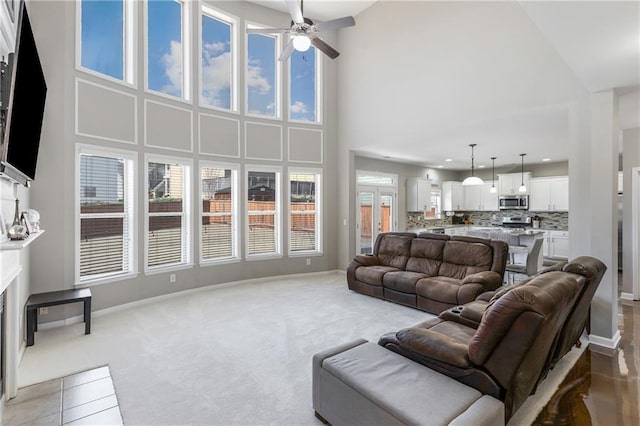 carpeted living room with ceiling fan and a towering ceiling