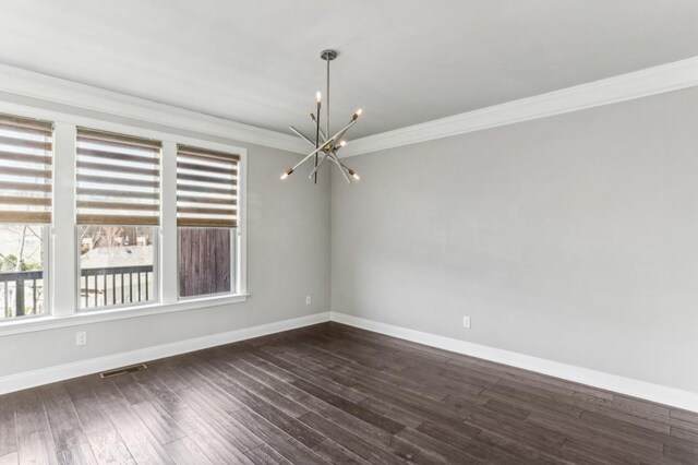 empty room featuring dark hardwood / wood-style flooring, ornamental molding, and a chandelier