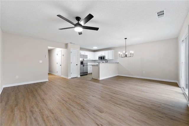 89 Prospect Path, Hiram, GA 30141 - unfurnished living room featuring a chandelier, ceiling fan, light wood finished floors, baseboards, and a textured ceiling