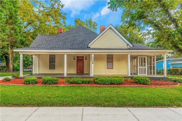 farmhouse-style home with a front yard and covered porch