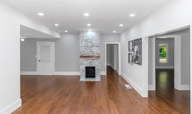 unfurnished living room featuring a stone fireplace, recessed lighting, wood finished floors, visible vents, and baseboards