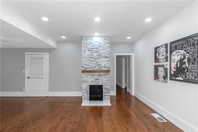 unfurnished living room with baseboards, visible vents, wood finished floors, a fireplace, and recessed lighting