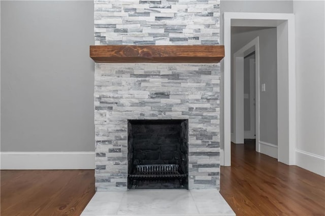 interior details with wood finished floors and a stone fireplace