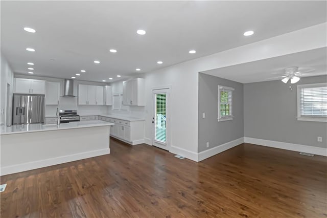 kitchen featuring visible vents, wall chimney exhaust hood, appliances with stainless steel finishes, dark wood-style flooring, and light countertops