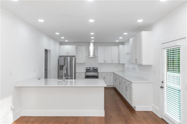 kitchen featuring stainless steel appliances, a peninsula, white cabinetry, light countertops, and wall chimney range hood