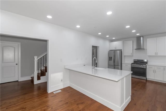 kitchen featuring wall chimney exhaust hood, dark wood-type flooring, a peninsula, stainless steel appliances, and a sink