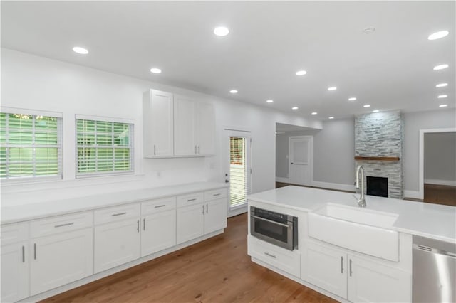 kitchen featuring stainless steel appliances, a wealth of natural light, white cabinetry, a sink, and wood finished floors