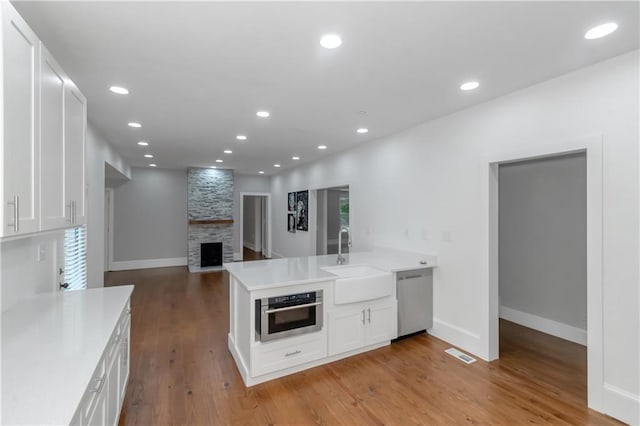 kitchen with visible vents, white cabinets, appliances with stainless steel finishes, a peninsula, and a sink