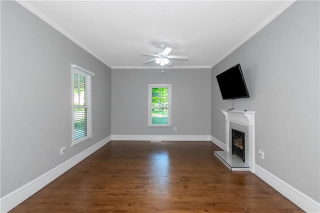 unfurnished living room with ornamental molding, a glass covered fireplace, a ceiling fan, wood finished floors, and baseboards