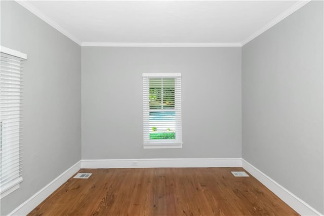 empty room featuring crown molding, visible vents, and baseboards