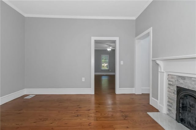 unfurnished living room with baseboards, a fireplace, wood finished floors, and crown molding