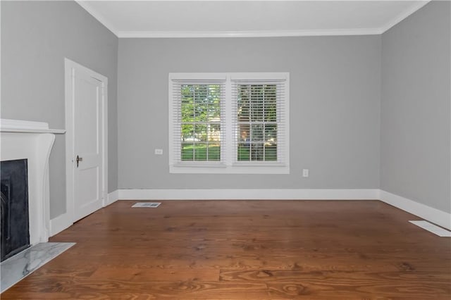 unfurnished living room with visible vents, a fireplace with flush hearth, ornamental molding, wood finished floors, and baseboards