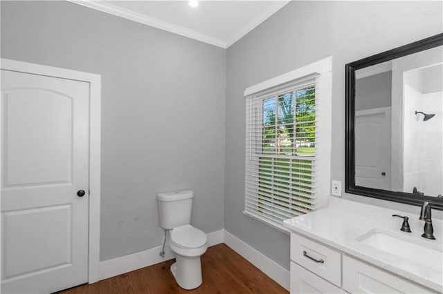 bathroom with toilet, wood finished floors, vanity, baseboards, and crown molding