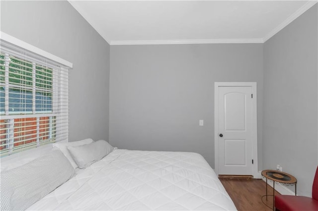 bedroom with ornamental molding and wood finished floors