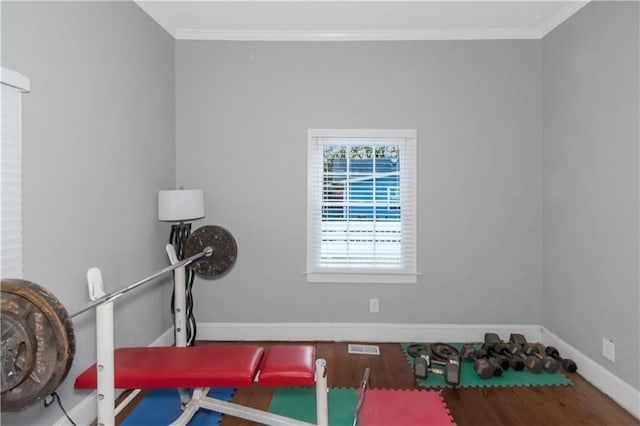 exercise room with visible vents, crown molding, baseboards, and wood finished floors