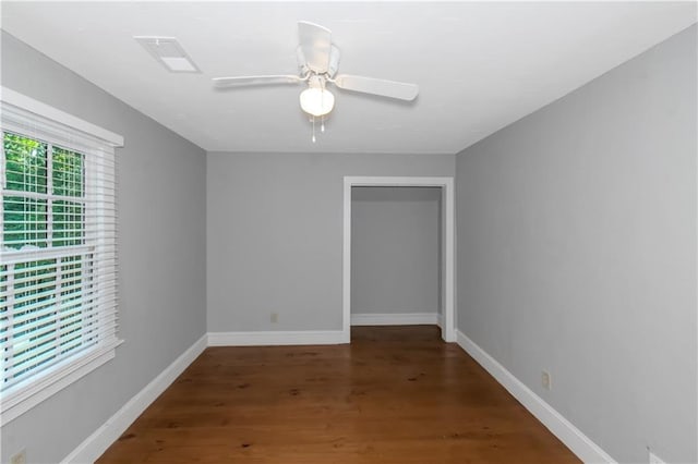 empty room featuring visible vents, wood finished floors, a ceiling fan, and baseboards