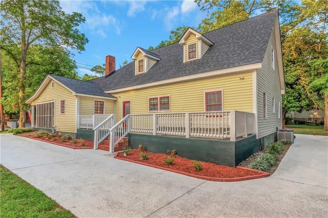 cape cod home featuring a porch, roof with shingles, a chimney, and central AC unit