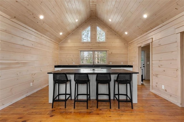 kitchen featuring dark countertops, wood ceiling, light wood-type flooring, lofted ceiling, and a kitchen breakfast bar