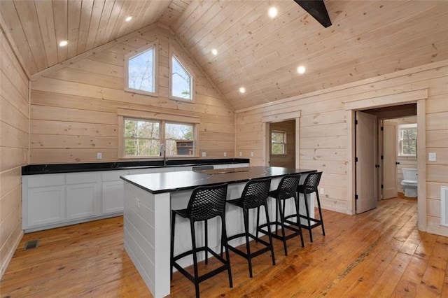 kitchen with dark countertops, light wood-style flooring, a kitchen breakfast bar, and a center island