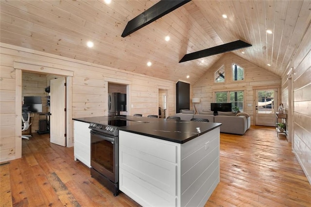 kitchen featuring dark countertops, wood ceiling, freestanding refrigerator, and range with electric cooktop