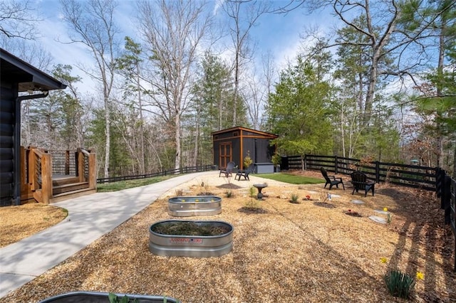 view of yard with an outbuilding, a fire pit, and fence